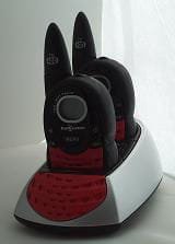 A pair of small walkie-talkies sitting in their twin charging dock